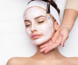 Woman receiving facial mask at beauty salon