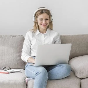 Vrouw op de bank met een laptop en koptelfoon op